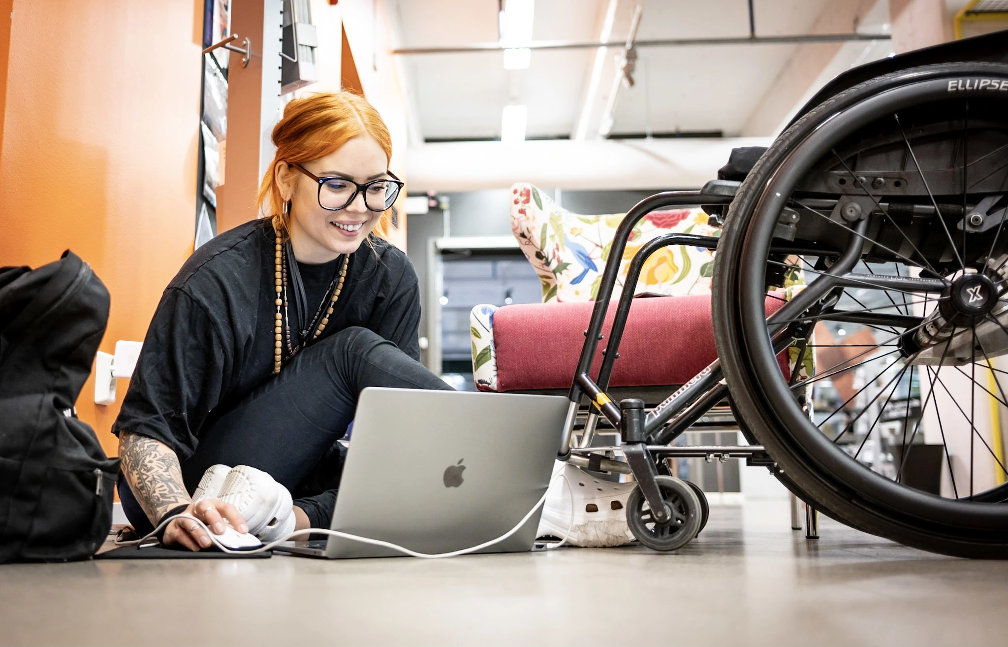Fashion designer Louise Linderoth works on her laptop, sitting on floor. Panthera manual chair